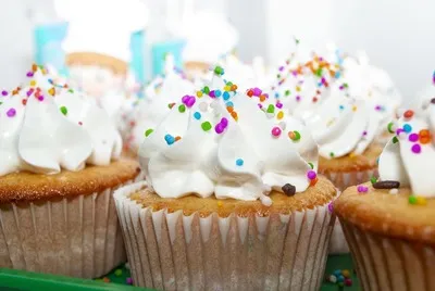 Ilustración de tres cupcakes con crema rosada sobre un plato